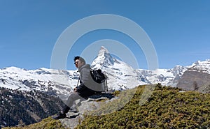 A man with backpack sitting on rock with Matterhorn mountain view in Switzerland