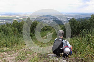 Man with a backpack sitting by the trail on Mount Tserkovka, Belokurikha city, Russia