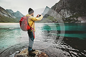 Man with backpack taking photo by smartphone