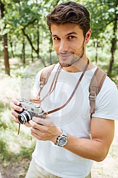 Man with backpack taking photos using old camera in forest