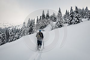 Man with backpack trekking in mountains. Cold weather, snow on hills. Winter hiking