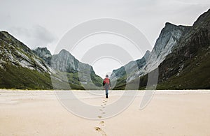 Man with backpack walking away alone at sandy beach