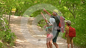 Man with backpack walking with boy and girl at road in mountains. Travel lifestyle concept adventure outdoor summer