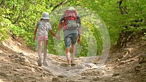 Man with backpack walking with boy and girl at road in mountains. Travel lifestyle concept adventure outdoor summer