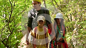 Man with backpack walking with boy and girl at road in mountains. Travel lifestyle concept adventure outdoor summer