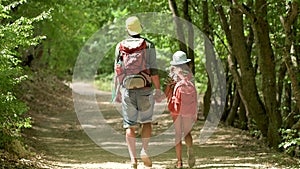Man with backpack walking with girl at road in mountains. Travel lifestyle concept adventure outdoor summer vacations