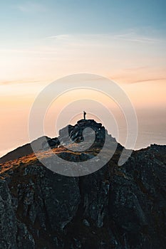 Man backpacker standing on mountain summit alone active travel in Norway hiking outdoor healthy lifestyle