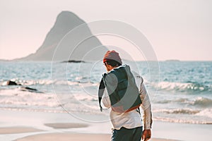 Man backpacker walking alone on sea beach solo traveling