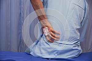 A man with backpain sitting on the patient bed