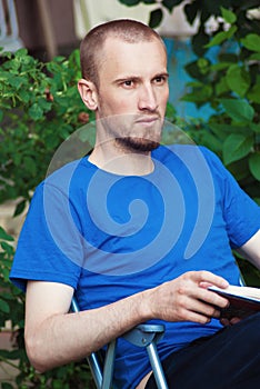 Man at backyard drinking coffee and reading book