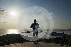 Man with bag on back looking at ocean at sunset in Croatia