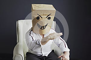 A man with a bag on his head, with a drawn angry emoticon, gloats emotionally.