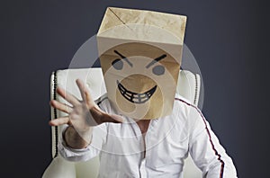 A man with a bag on his head, with a drawn angry emoticon, gloats emotionally.