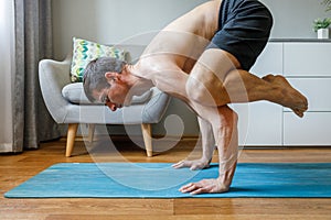 Man in bakasana pose doing vinyasa yoga flow