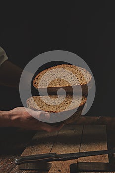 Man baker holds in his hands halves of rye bread,