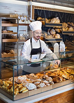 Man baker showing warm tasty croissant