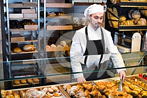 Man baker showing warm tasty croissant