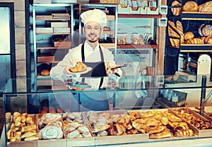 Man baker showing warm tasty croissant