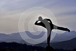 Man balancing on one leg on mountaintop