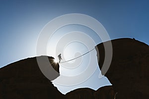 A man balancing walking on rope over precipice. Business, risk taking, challenge,bravery, and concentration