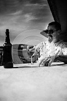 A man on the balcony is sitting at a table with a glass