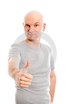 Man with bald head and thumb up is looking friendly in to the ca