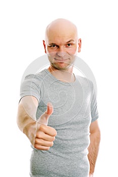 Man with bald head and thumb up is looking friendly in to the ca