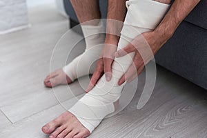 Man bandaging injured ankle. Injury leg. First aid for sprained ligament or tendon