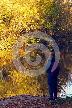 A man on the bank of a fast, small river looks into the distance.