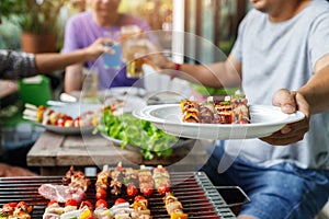 A man with a barbecue plate at a party between friends. Food, people and family time concept