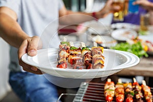 A man with a barbecue plate at a party between friends. Food, people and family time concept