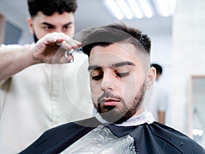 Man in barber shop getting haircut for his hair, beard, and eyebrows