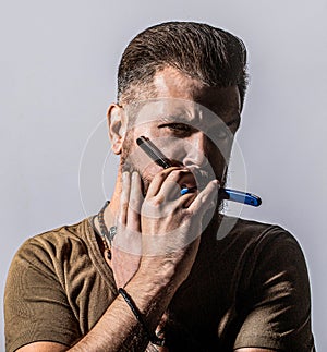 Man in barbershop. Straight razor, barbershop, beard. Handsome bearded hairdresser is holding a straight razor while