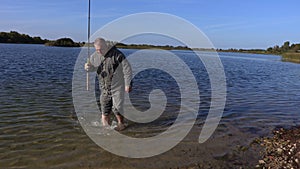 Man with bare feet and fishing rod in lake