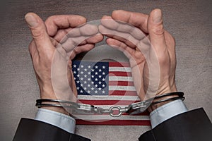 A man with bare hands in handcuffs sits at a table in front of a blank sheet of paper and a fountain pen. Concept: the detainee