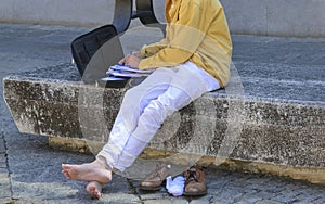 Man barefoot sitting on the bench and working