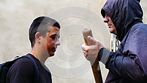 Man with a baseball bat against teenager