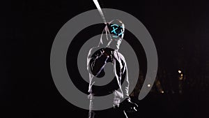 Man with a baseball bat in mysterious glowing mask. Anonymous swings on a black