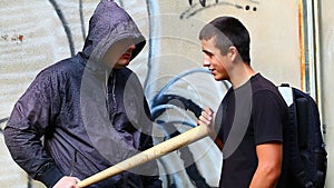 Man with a baseball bat talking with teenager