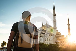 A man in a baseball cap with a backpack next to the blue mosque is a famous sight in Istanbul. Travel, tourism