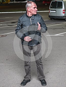 A man with a baseball cap in his hands at night on the street