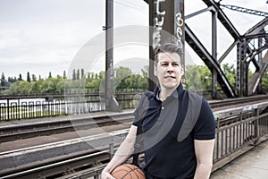 Man With a Basketball Posing Near Railway Tracks