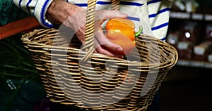 Man with a baskets selecting bell pepper in organic section