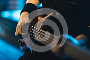 Man bass guitarist playing electrical guitar on concert stage