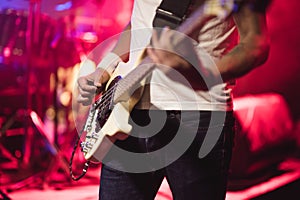 Man bass guitarist playing electrical guitar on concert stage