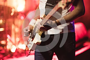 Man bass guitarist playing electrical guitar on concert stage