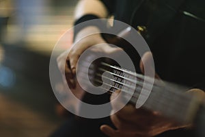 Man bass guitarist playing electrical guitar on concert stage