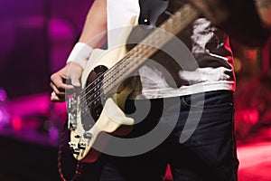 Man bass guitarist playing electrical guitar on concert stage