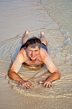 Man in bathingsuit is lying at the beach