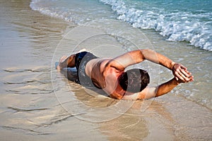 Man in bathingsuit lying at the beach